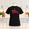 Back of a Door County Coffee Cherry logo t-shirt in a white kitchen