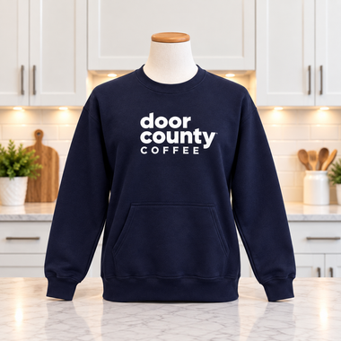 Navy blue Door County Coffee front pocket crew neck sweatshirt on white counter