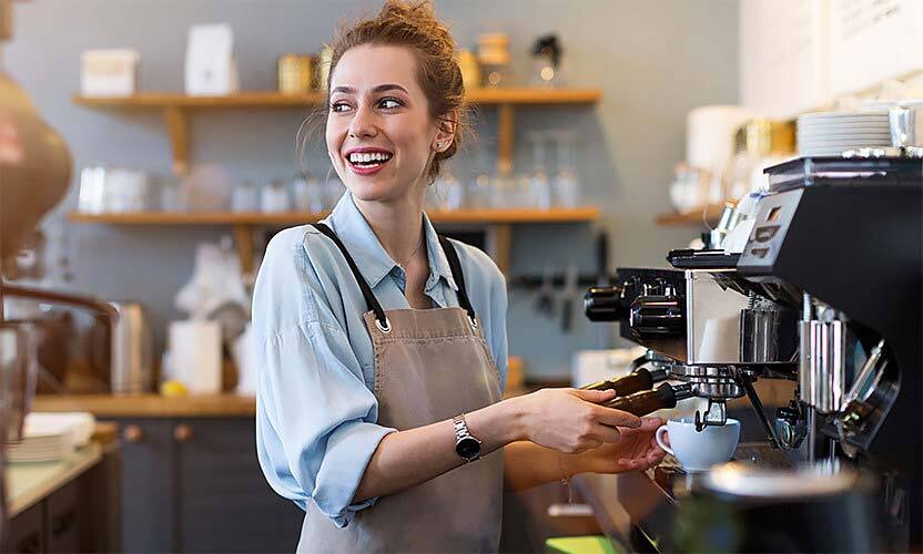 a barista smiling while operating an espresso machine