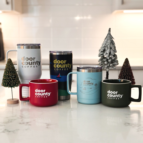 an arrangement of holiday inspired grourmet cocoa containers with mini christmas trees on a countertop