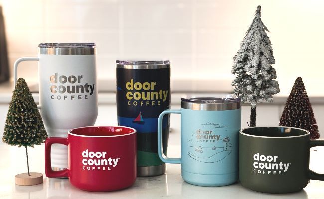an arrangement of holiday inspired grourmet cocoa containers with mini christmas trees on a countertop
