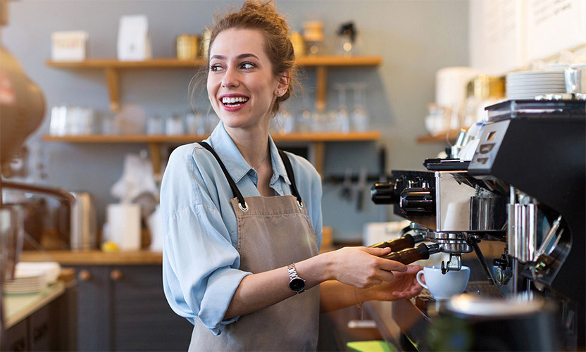 a barista smiling while operating an espresso machine
