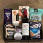Gift hamper with wine, cheese, crackers, chocolate, dip, fruit paste and pretzels.