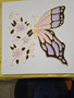A hand  painted image of a butterfly in shades of gold.