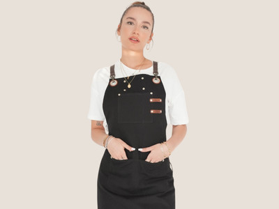 Female model wearing a black personalized canvas apron with leather straps by Sade New York