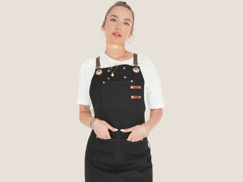 Female model wearing a black personalized canvas apron with leather straps by Sade New York