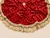 Close-up of handmade red velvet Christmas tree skirt with abundant crystal embellishments, luxurious gold tassels and rich velvet texture.