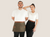 Two models wearing artisan cotton canvas half aprons with leather belts and towel loops