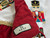 Close-up of embroidered red nutcracker soldier on a luxury Christmas tree skirt with white velvet panels, red velvet ruffles and gold tassel fringe.