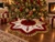 Luxury 55-inch red and white velvet nutcracker Christmas tree skirt by SADE New York, featuring embroidered toy soldiers, gold tassel fringe and star-shaped design beneath a traditional Christmas tree in an elegant holiday living room.
