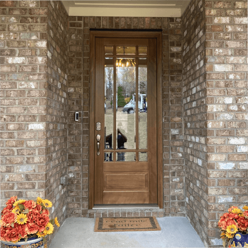 Mahogany 9 Lite prairie style single front entry door with clear bevel glass shown on a brick home under a covered porch for timeless curb appeal. Available at GrandEntryDoors.com.