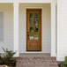 Mahogany 8 Lite single front entry door with clear beveled glass shown on a covered front porch with brick steps, adding elegance and warmth to any home. Available at GrandEntryDoors.com.