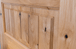 Close-up view of knotty alder wood grain showcasing natural knots, rich texture, and warm color variations that create a rustic, handcrafted appearance. Available at GrandEntryDoors.com.