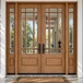 Mahogany 9 Lite prairie style double front entry door with sidelights and clear bevel glass shown on a beautiful front porch, adding elegance and warmth. Available at GrandEntryDoors.com.