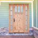 Knotty alder Craftsman front door with vertical plank panels, three lite glass, and matching sidelights creating a warm, inviting entryway.