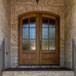 Flemish glass 6 lite arch top mahogany double door within a well-covered brick entry combines charm and durability. Available at Grandentrydoors.com.