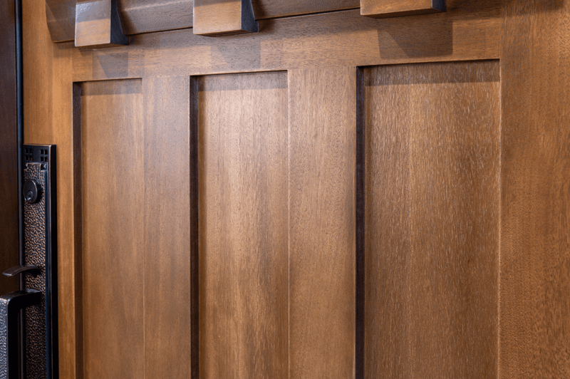 Close-up of mahogany door panel profile highlighting smooth contours, refined craftsmanship, and rich wood grain detail, shown with stain applied, ships unfinished. Available at GrandEntryDoors.com.