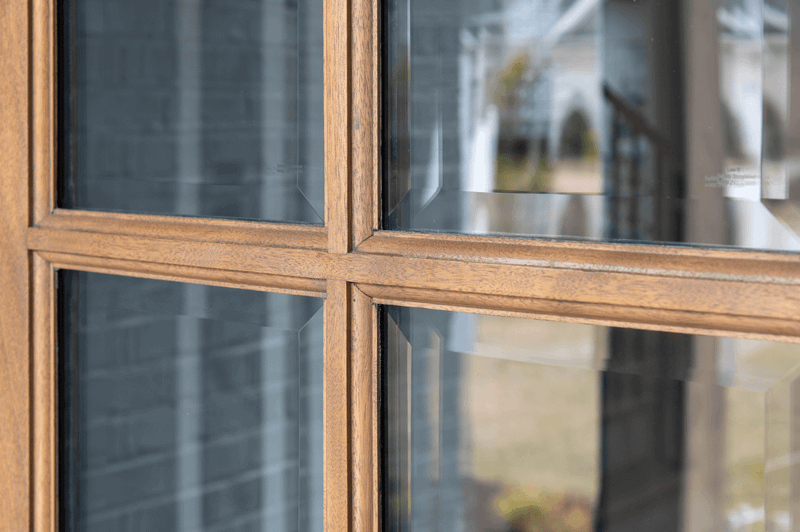 Close-up of mahogany true divided lite (TDL) profile showing precise muntin detailing, clear bevel glass, and smooth handcrafted finish. Available at GrandEntryDoors.com.