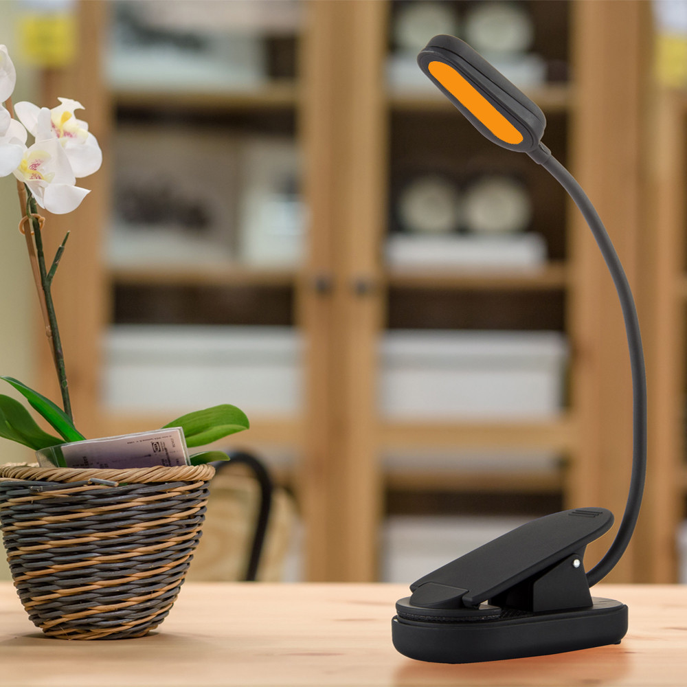 Amber clip-on reading light bringing a warm glow to a bedside table