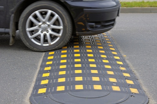 Vehicle crossing a modular speed hump with yellow markings