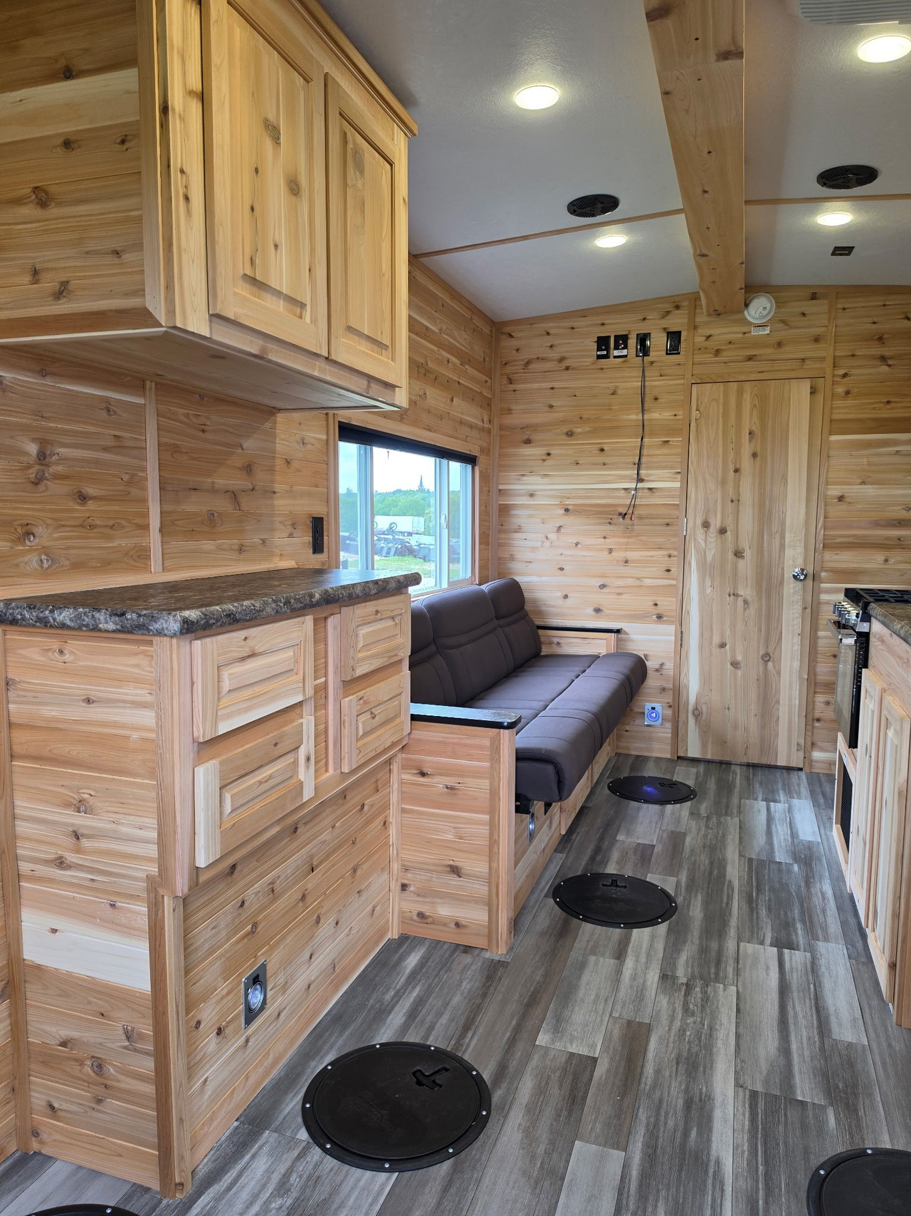 Finished cedar Ice Castle fish house interior with fishing holes seating and cabinetry