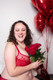 A woman wearing a luxury, high quality red French bra by Empreinte holds roses and laughs