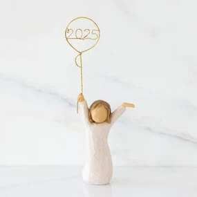 Front view: standing figure in cream dress, arms raised, holding gold wire balloon with 2025 written in gold wire inside