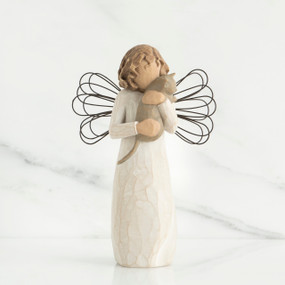 Faceless angel figurine facing forward holding grey cat wearing white dress and black wire wings