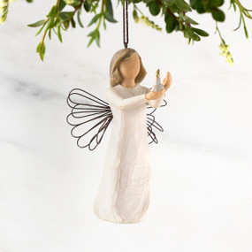 Figure with short brown hair wearing cream dress holding out a candle in her hands, ornament hook attached to head