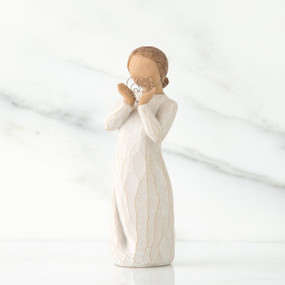 Small girl figurine faceless wearing white dress and holding silver heart figurine