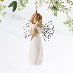Figure in cream dress with wire wings, holding gray cat in arms, ornament loop attached to head