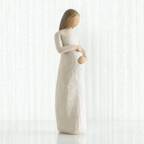 Faceless pregnant woman figurine wearing white dress with hands clutching her stomach