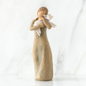 Faceless woman figurine standing wearing light tan dress holding white lamb in her arms