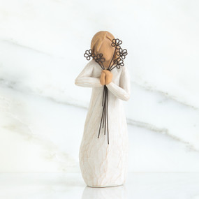 Close view of blonde woman figurine in white dress holding black flower boquet