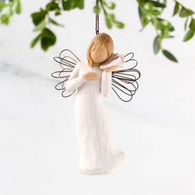 Female angel with wire wings in cream dress, holding pink shell up to ear, ornament loop attached to head
