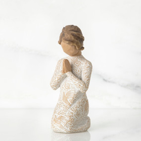 Small faceless girl figurine wearing white/tan bird design dress, kneeling and praying