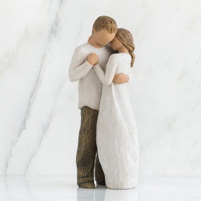 Faceless couple standing holding hands facing one another - she is in white dress, he is in white shirt and brown pants
