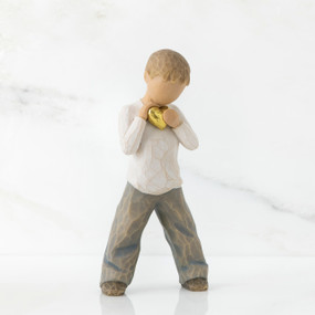 Young boy faceless figurine in white shirt and blue jeans holding gold heart figurine standing up