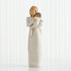 Faceless woman figurine in white dress holding brown haired baby in white clothes