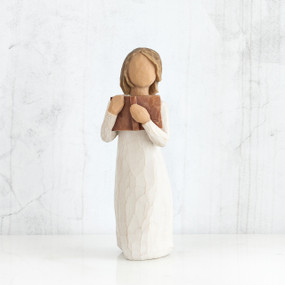 Young faceless girl figurine standing up wearing white dress holding brown book to her face