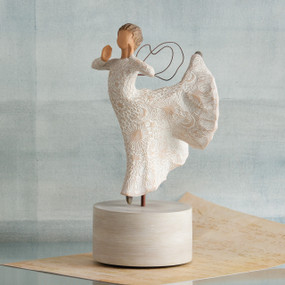 Faceless woman figurine wearing white dress dancing on white round plaque