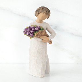 Girl figurine with short brown hair in white dress holding purple flowers