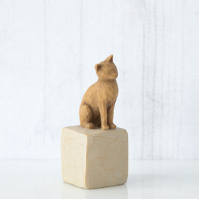Golden cat figurine sitting on white rock