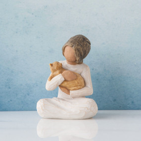 Small faceless girl figurine sitting down holding golden cat in her arms