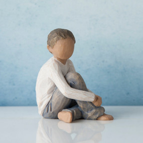 Faceless young boy figurine sitting down wearing white shirt and blue jeans