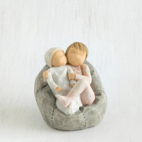 Two small baby figurines hugging another laying on grey beanbag