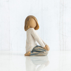 Small little girl figurine sitting on her knees, faceless, wearing white shirt and blue jeans
