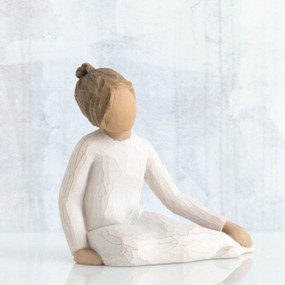Faceless girl figurine sitting down wearing white dress