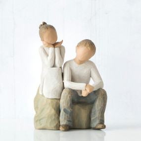 Young faceless girl figurine sitting on rock next to young facless boy figurine sitting on rock