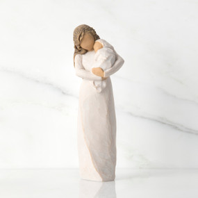 Front view of brunette woman figurine in white dress holding swaddled baby